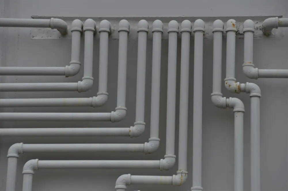 Tubulação cinza instalada na parede, com várias curvas